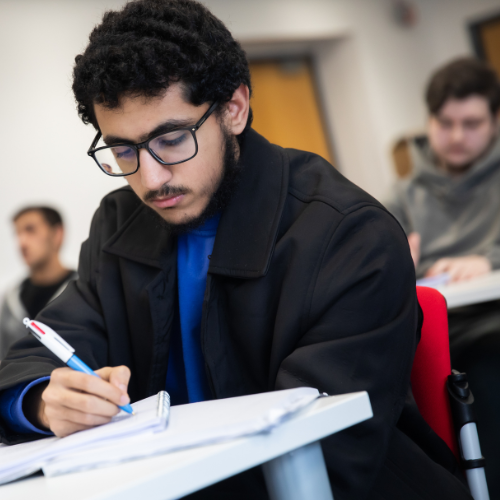 Student writing in a notebook during a lecture